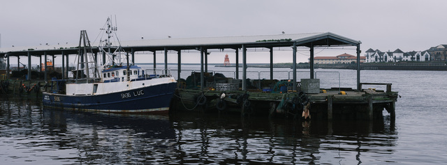 A fishing boat is moored to a wharf at North Shields fish quay on a grey day